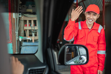 close up of mechanic in red uniform with forward gesture when customer arrives at the workshop