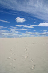 Fototapeta na wymiar Footprints in the white sand under the blue sky