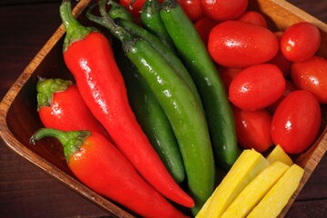 Wood bowl of peppers, tomatoes, and squash.