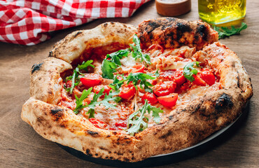 Pizza Margherita on a wooden background. Freshly baked crispy pizza with tomatoes and mozzarella.