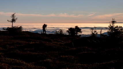 Silhouette of a photographer taking picture from a tripod early in the morning with good light on an inversion day.