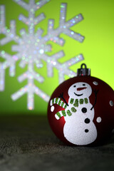 Christmas sphere with a design of a snowman with a tie, in the background an artificial snowflake