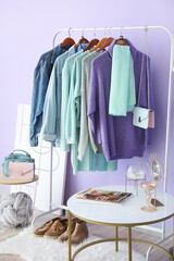 Rack with autumn clothes in interior of modern room