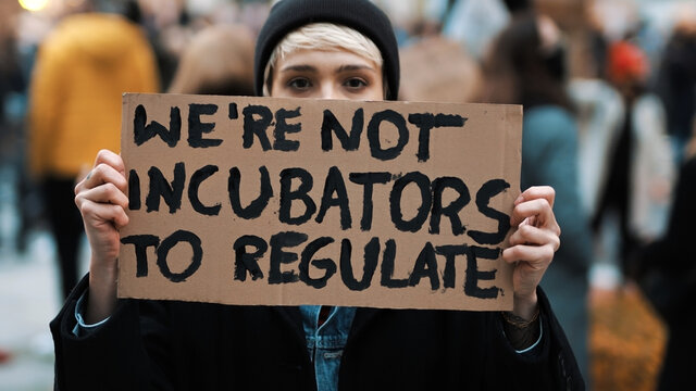Womens march. Young woman with face mask holding banner sign - We are not incubators to regulate. protest against strict abortion laws. High quality photo