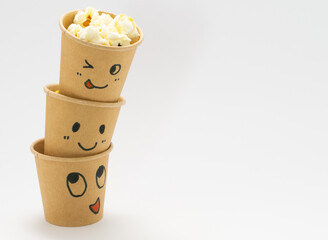 顔が書かれた紙コップにはいったポップコーン