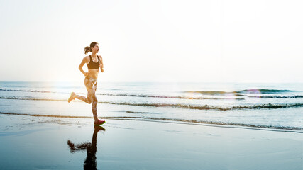 Sportive woman jogging at a beach © Rawpixel.com