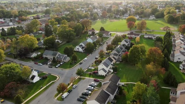 Small town in USA. Homes and rental apartment units with colorful trees. Rising aerial pull-back drone shot.