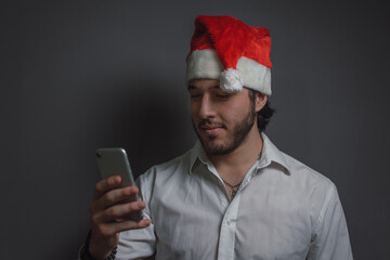 hombre caucásico enviando mensaje de texto con su celular en navidad con lugar para copyspace