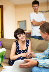 Adult woman and her incredulous young son having meeting with agent at home