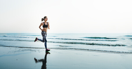 Sporty woman running at the beach - Powered by Adobe