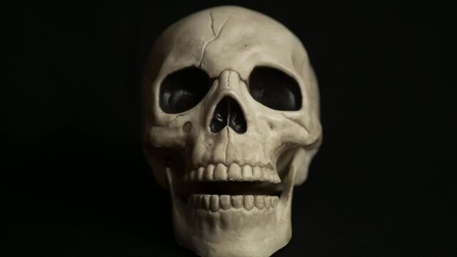 Stop motion human skull gnashing teeth on black background medium shot