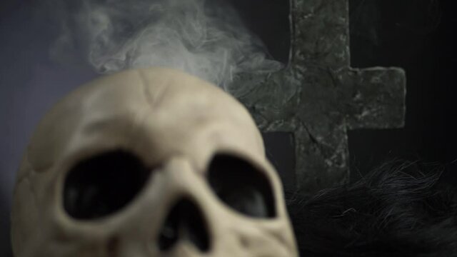 Human skull on with cross and smoke background zoom in shot