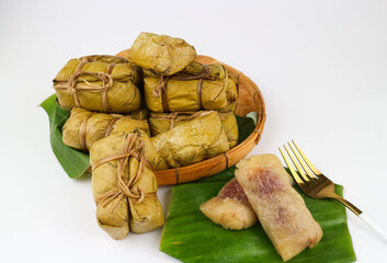 Khao tom mud- Steamed sticky rice filled with banana and wrapped with banana leaf in bamboo basket on white background - Thai dessert/snack