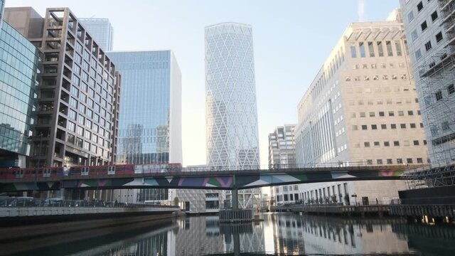 Red London DLR train passing over bridge behind Newfoundland building Canary wharf London