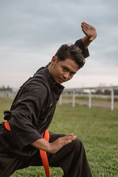 Asian men wearing pencak silat uniforms with pasang movements on outdoor background