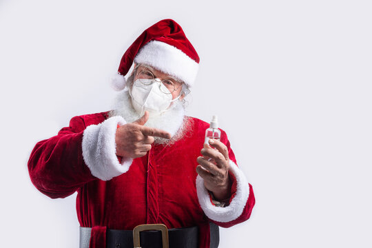 Santa Claus wearing a mask, pointing bottle of hydroalcoholic gel in white background