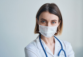 Woman doctor in a medical mask with a stethoscope around her neck