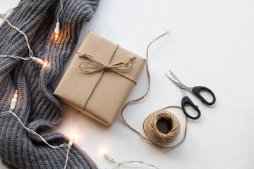 gift box for special in christmas and happy new year festival with rope ,scissors knitting wool scarf in winter season arrangement flat lay style on background white wooden