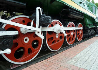 Red driving wheels of a steam locomotive, connected by levers.