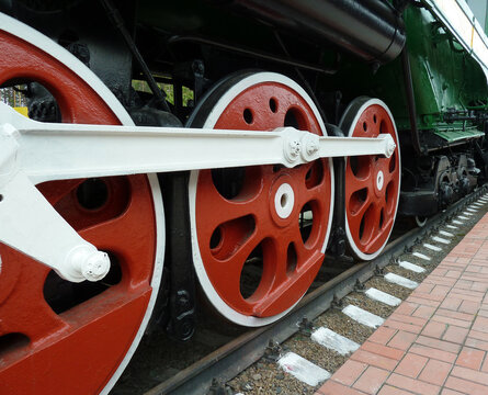 Red driving wheels of a steam locomotive, connected by levers.