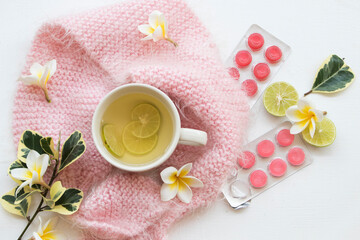 Fototapeta na wymiar herbal honey lemon healthy drinks health care for sore throat ,lozenge with pink knitting wool scarf of lifestyle woman relax in winter season and flowers frangipani decorate on background white