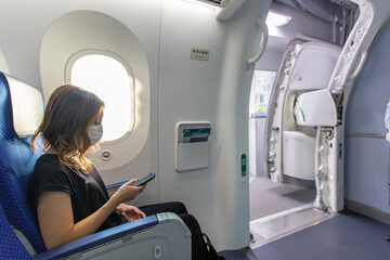 Go to トラベルでマスク姿で飛行機に乗るアジアの若い女性