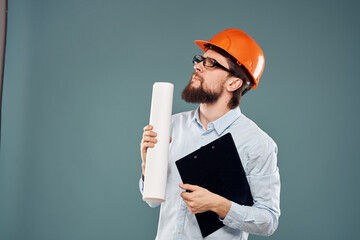 A male engineer in an orange hard hat with documents in the hands of construction drawings