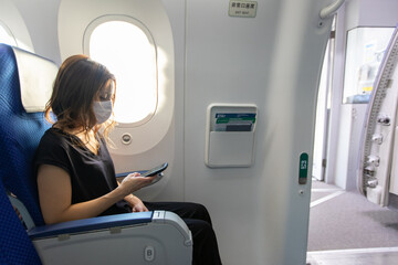 Go to トラベルでマスク姿で飛行機に乗るアジアの若い女性