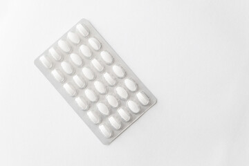 White pills tablets in package on a white background. Capsule pills in plastic pack for pharmacy and medicine.