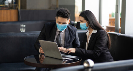 Two business colleagues at meeting in modern office interior. Businessman and businesswoman discussing work and using laptop computer in meeting indoors.
