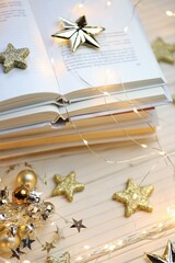 Winter books.Winter cozy reading. A pile of  books, shining stars and garlands on a white wooden table.Cozy mood.books close up. Book pages macro and shining garland. Winter Season.Christmas book