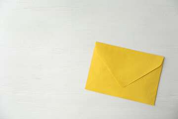 Yellow paper envelope on white wooden table, top view. Space for text