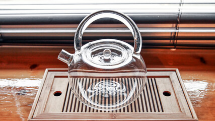 Glass Chinese kettle for cooking stands on the tea tray, close-up image.