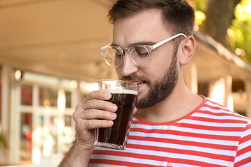 Handsome man with cold kvass outdoors. Traditional Russian summer drink