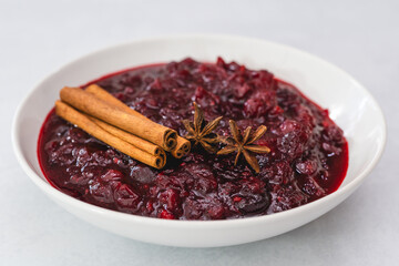 Cranberry sauce, cinnamon, anise star close up in a bowl on light background