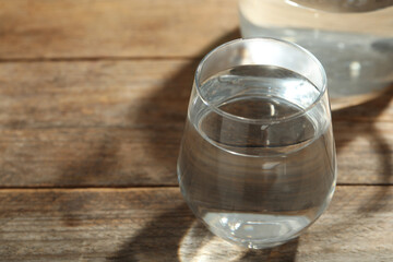 Glass of water on wooden table, closeup with space for text. Refreshing drink