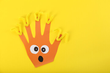 Funny orange hand shaped monster on yellow background, top view with space for text. Halloween decoration © New Africa