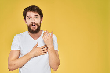 Bearded man white t-shirt emotions gestures with hands fun yellow background