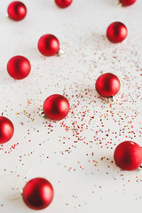 Red small decorative Christmas balls and colorful glitters on white background. Christmas and New Year concept