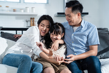 Asian family talking and sitting together on sofa in the living room.