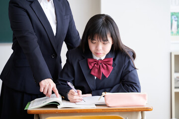 教室で先生に教えてもらう日本人女子中学生
