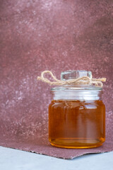 glass jar with honey on a Burgundy background