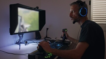Man playing a flight simulator on the computer, wearing a headset