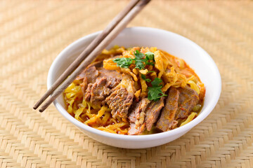 Fototapeta premium Northern Thai food (Khao Soi), Spicy curry noodles soup with beef in a bowl and chopsticks