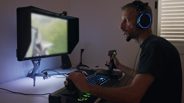 Man playing a flight simulator on the computer, wearing a headset
