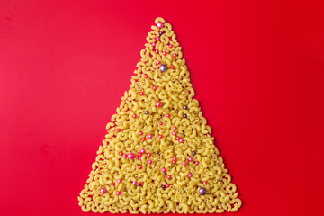 Christmas tree of pasta decorated with balls on a red background