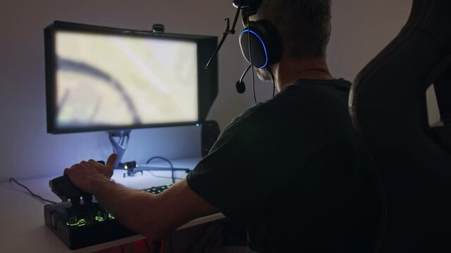 Man playing a flight simulator on the computer, wearing a headset