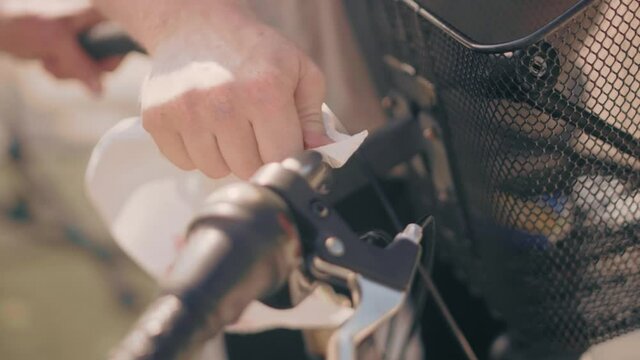 A bike handlebar with a basket being cleaned with a white sheet by a bike mechanic. Close up with shallow depth. Shot during warm summer sun. Shot in 4K.