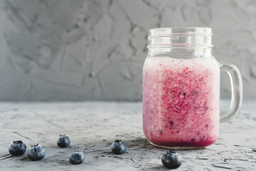 Homemade blueberry smoothie in a glass on concrete background. Healthy detox drink