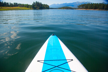 A paddle board floating on a beautiful mountain lake in Montana. Point of view photo of a scenic...